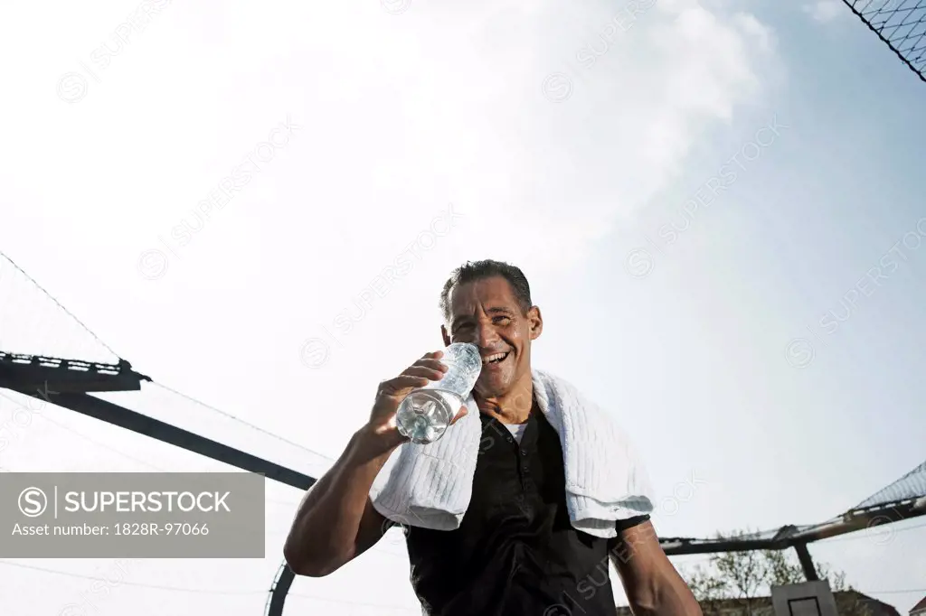 Mature man with towel around neck, drinking bottle of water and looking at camera, Germany,05/02/2013