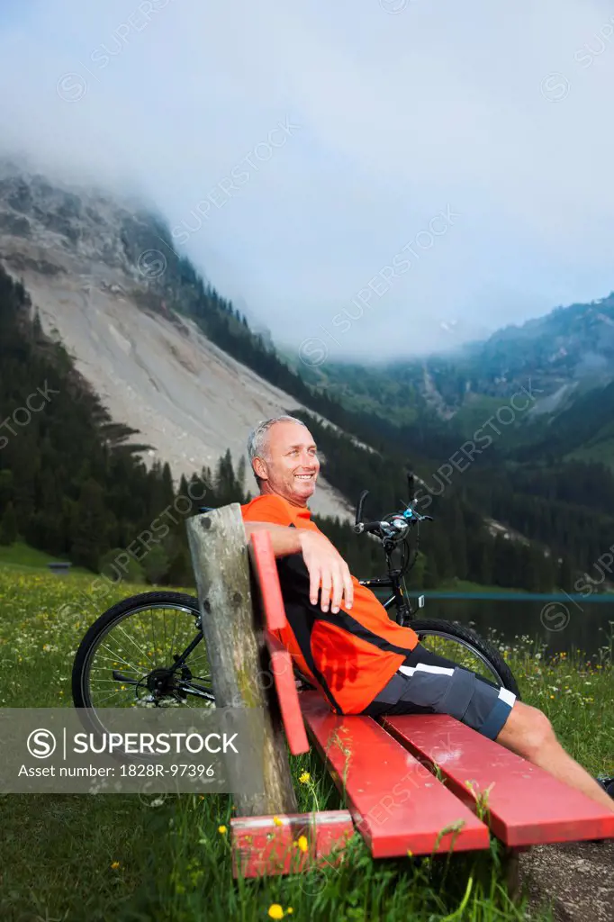 Mature Man on Bench by Lake with Mountain Bike, Vilsalpsee, Tannheim Valley, Tyrol, Austria,06/14/2013