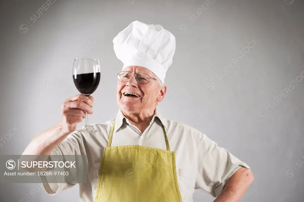 Senior Man with Red Wine wearing Apron and Chef's Hat, Studio Shot,06/04/2013
