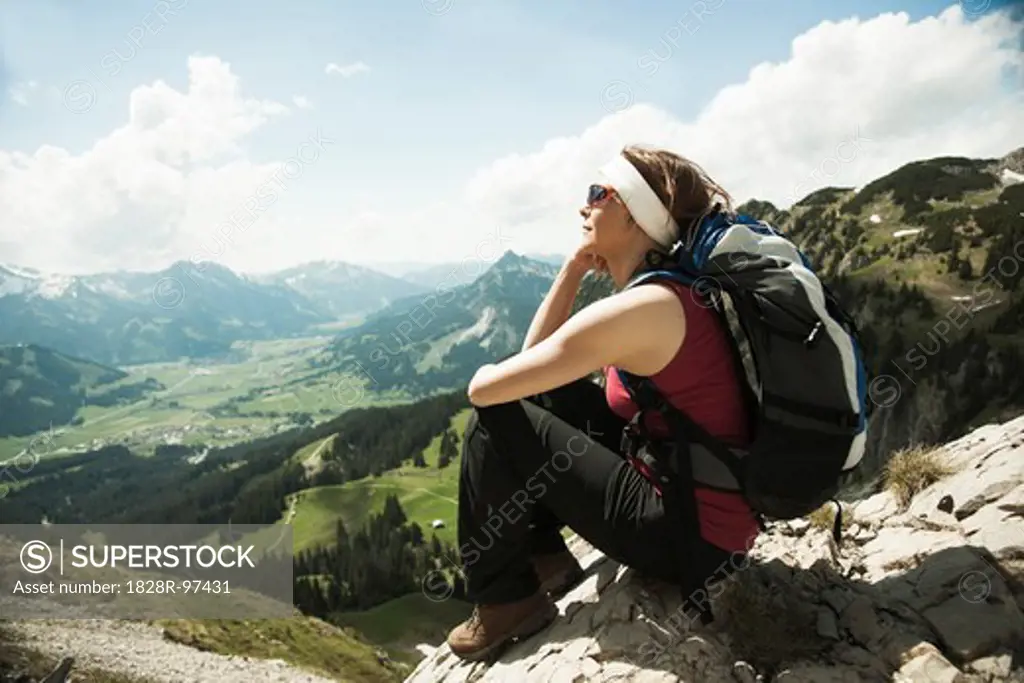 Mature woman sitting on cliff, hiking in mountains, Tannheim Valley, Austria,06/15/2013