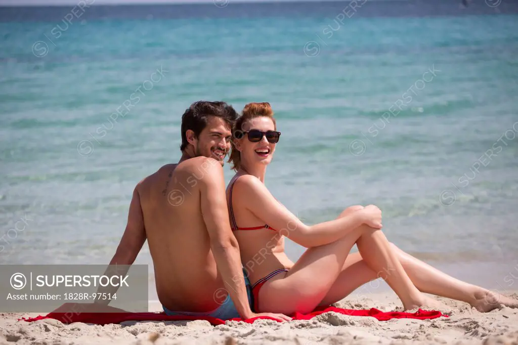 Young couple relaxing at the beach during summer holidays, Cala Cipolla, Chia Bay, Sardinia, Italy,05/21/2013