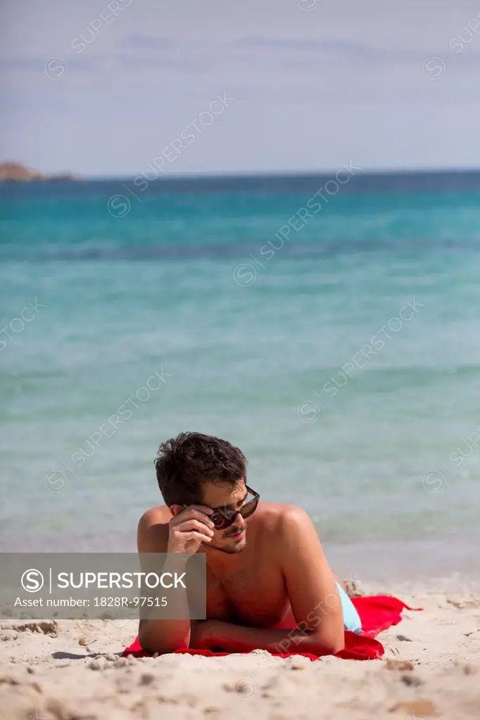 Young man relaxing at the beach during summer holidays, Cala Cipolla, Chia Bay, Sardinia, Italy,05/21/2013