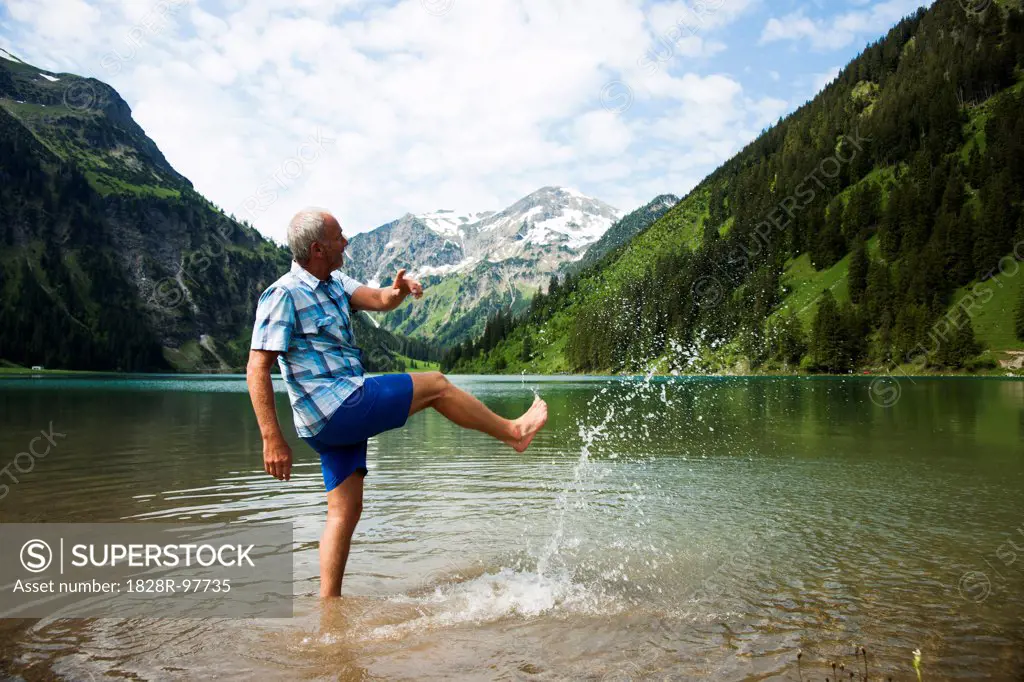 Mature man standing in lake, kicking water, Lake Vilsalpsee, Tannheim Valley, Austria,06/15/2013