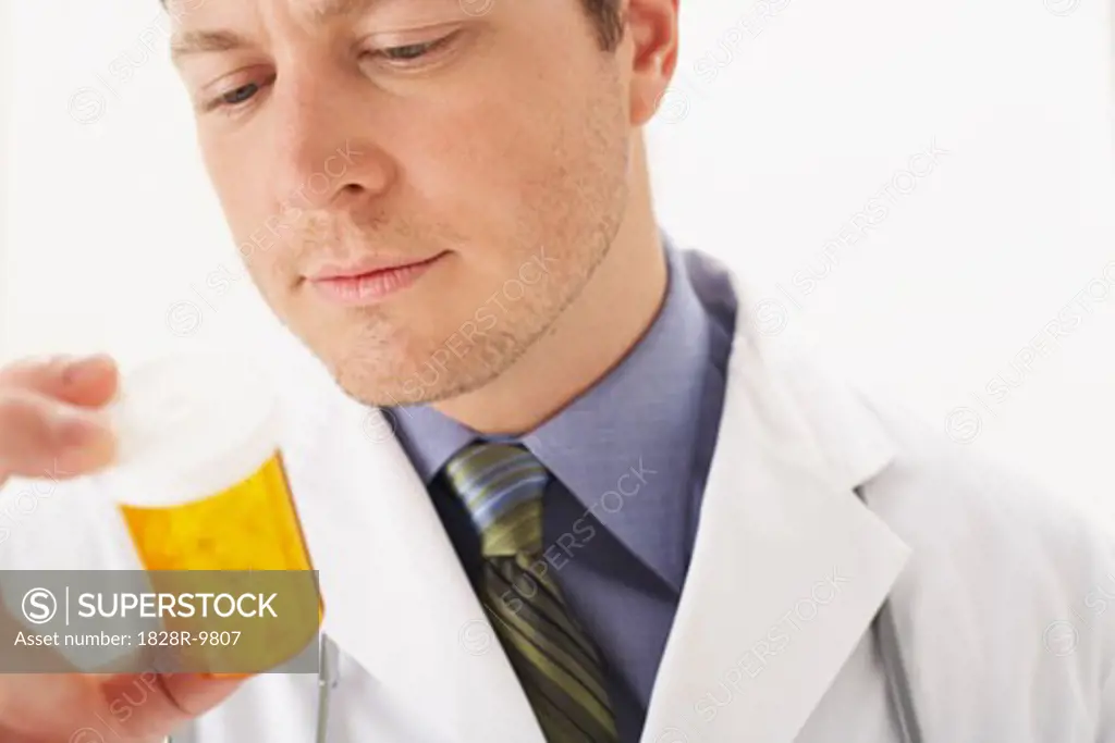 Doctor Looking at Bottle of Pills   