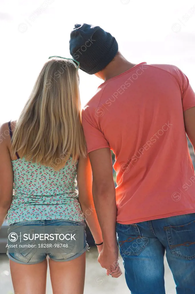 Backview of teenage boy and teenage girl holding hands, standing outdoors, Germany,08/21/2013
