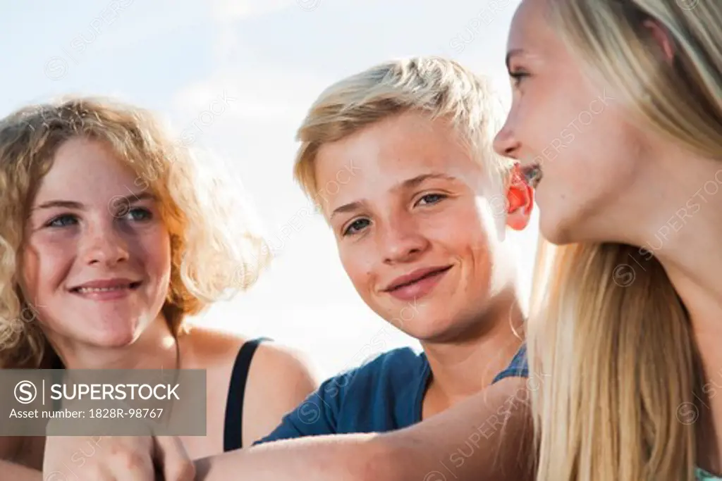 Close-up portrait of teenage girls and boy sitting outdoors, Germany,08/21/2013