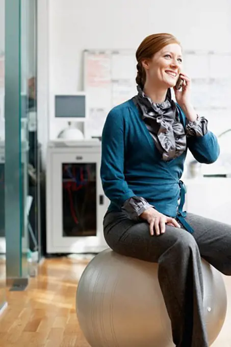 Business Woman with Cellular Phone and Exercise Ball   
