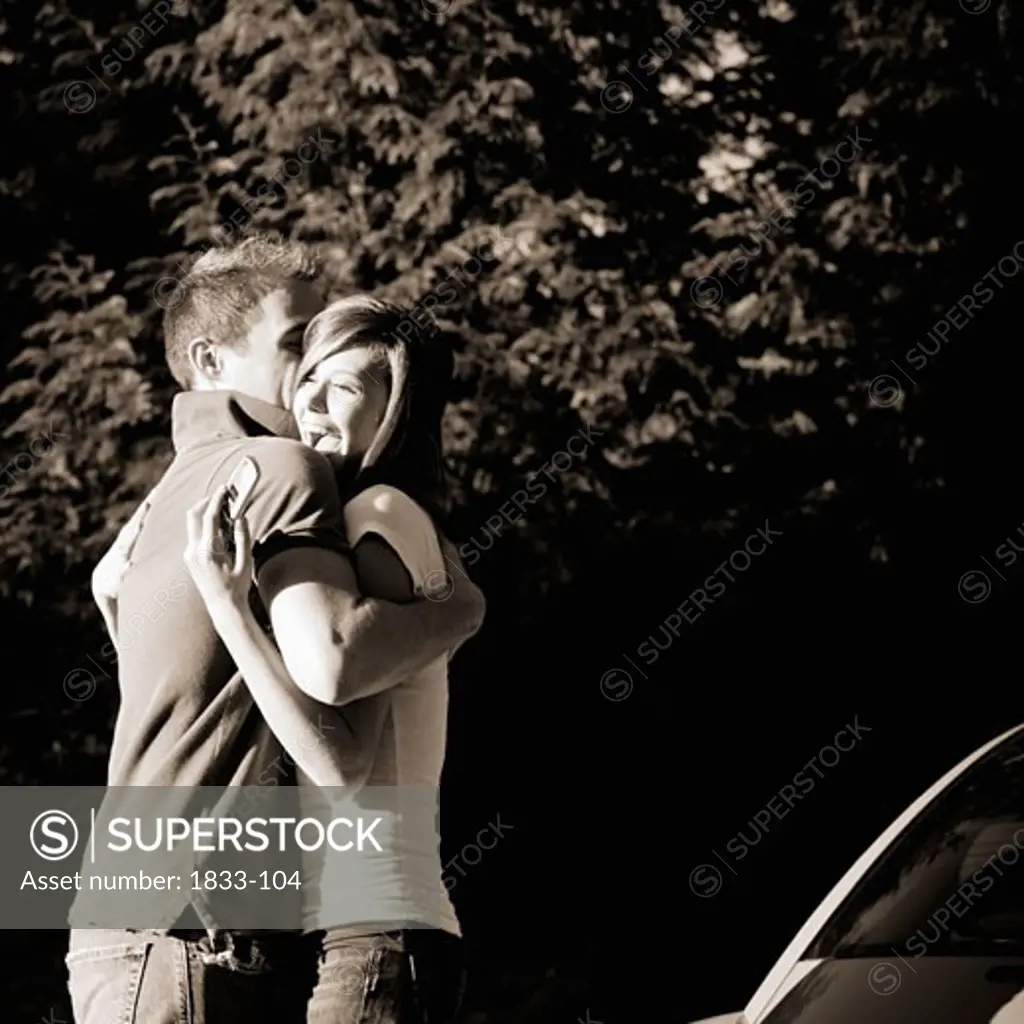 Young couple hugging, holding a cellular phone