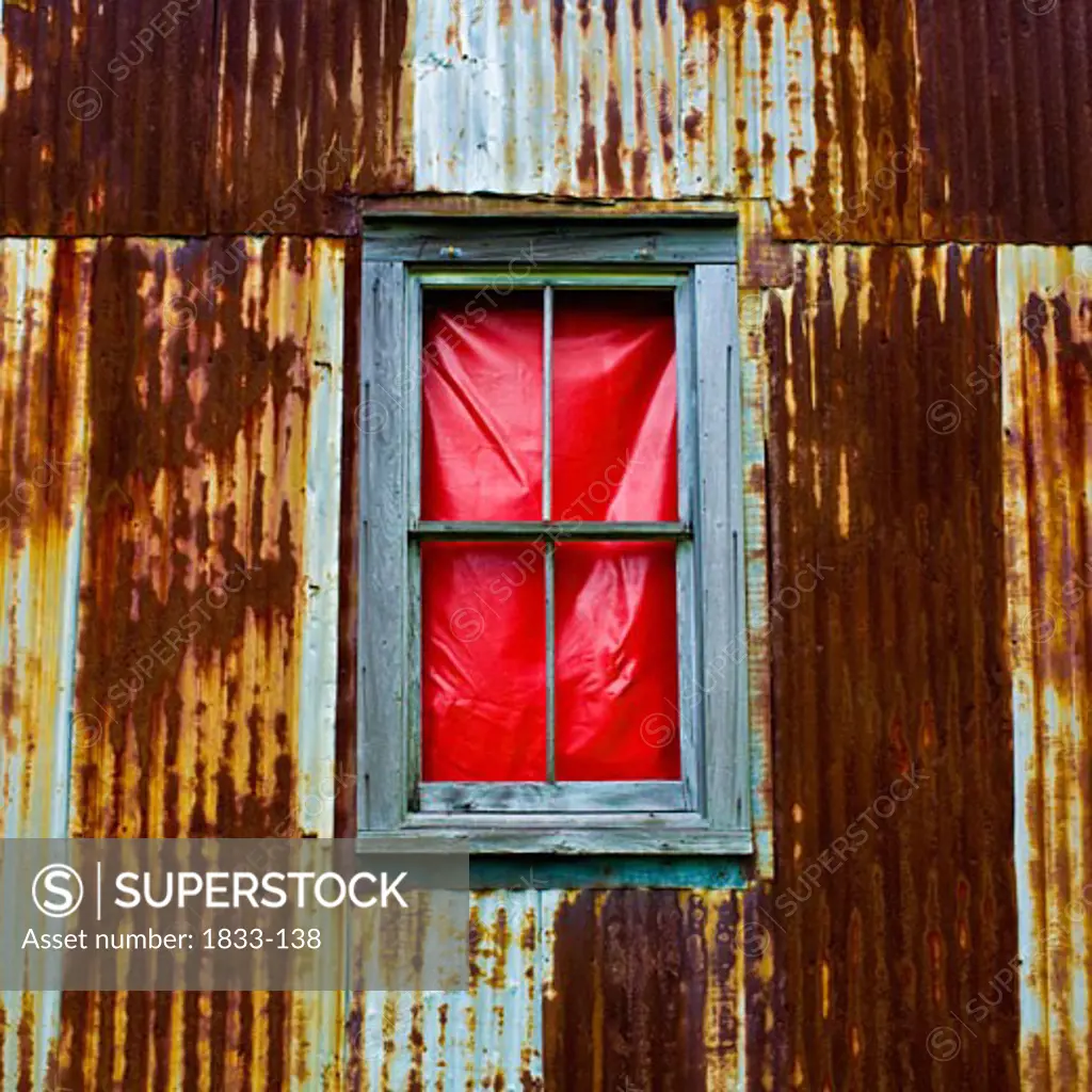 Close-up of a window in a rusty corrugated iron house