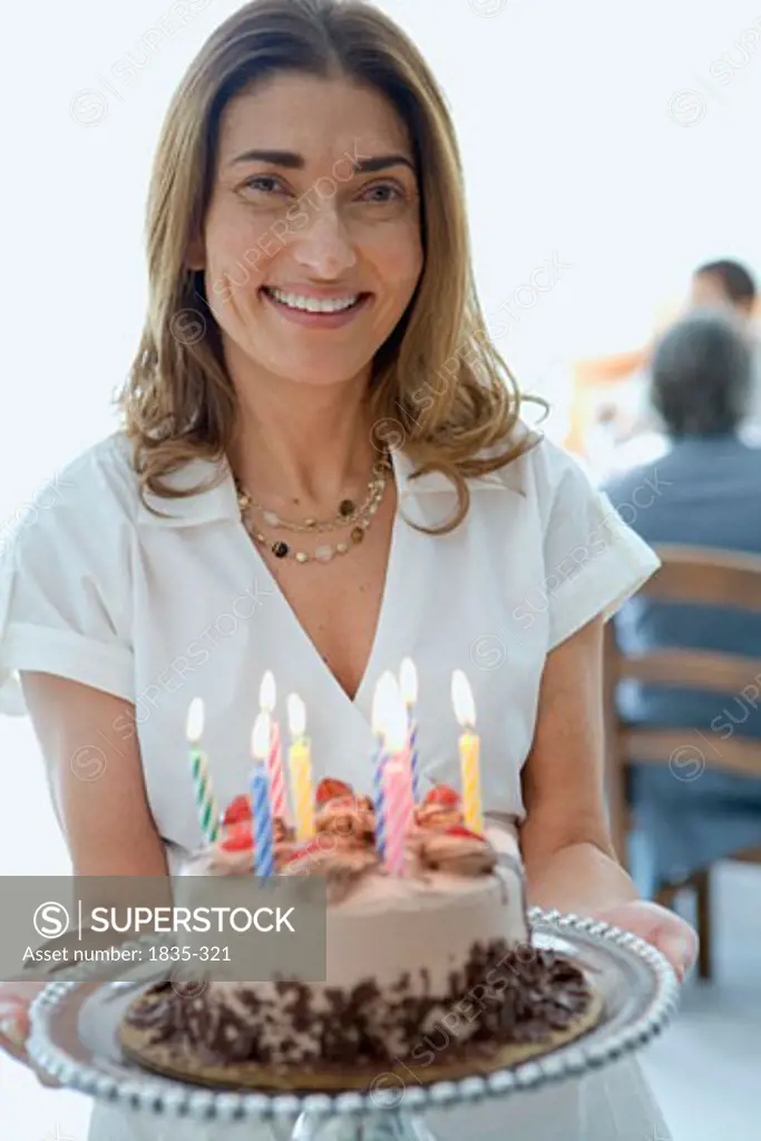 Close-up of a woman standing and holding a birthday cake