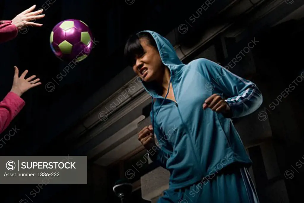 Low angle view of a young woman heading a soccer ball