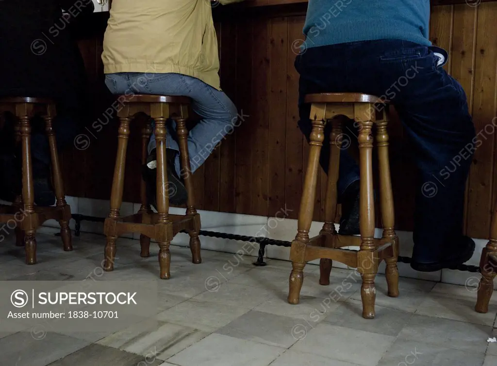 Men Sitting on Stools at Bar