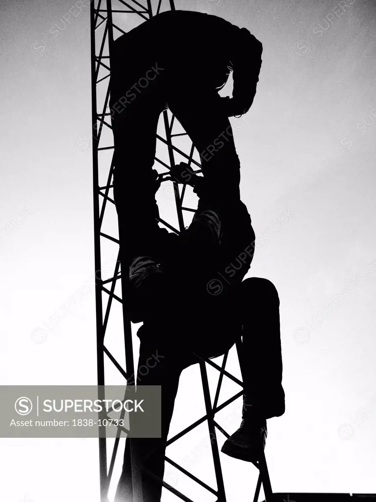 Two People Climbing Metal Tower