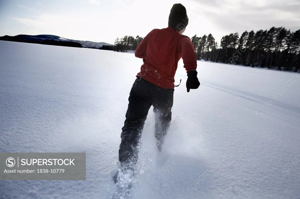 Woman Running Through Snow on Frozen Lake, Halsingland, Sweden