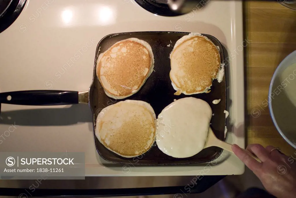 Pancakes on Skillet, One being Flipped