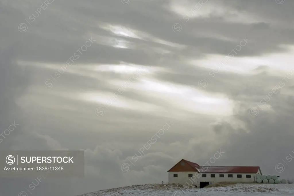 White Barn on Snowy Landscape Against Dramatic Clouds, Iceland