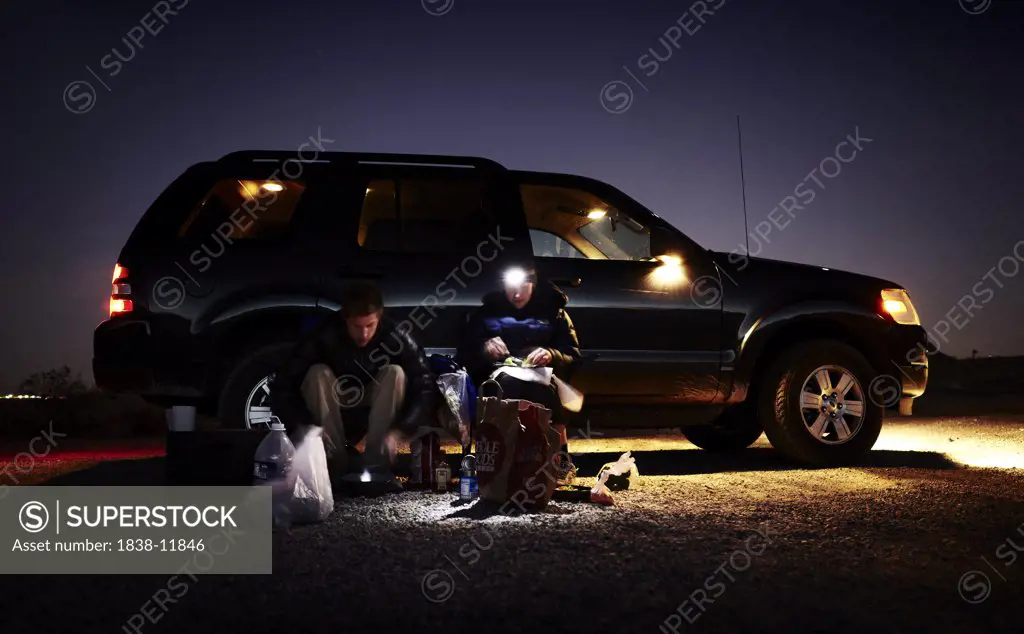 Couple Eating Outdoor Next To SUV at Night, Nevada, USA