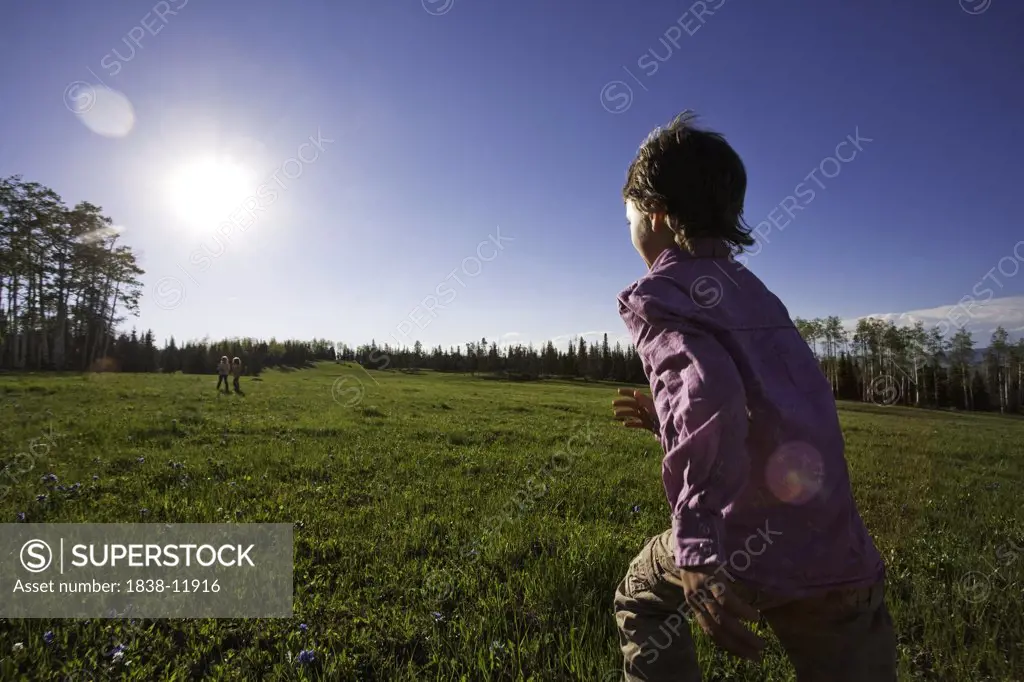 Young Girl in Pink Shirt Running To Two Other Children in Green Field, Rear View, Oak Creek, Colorado, USA