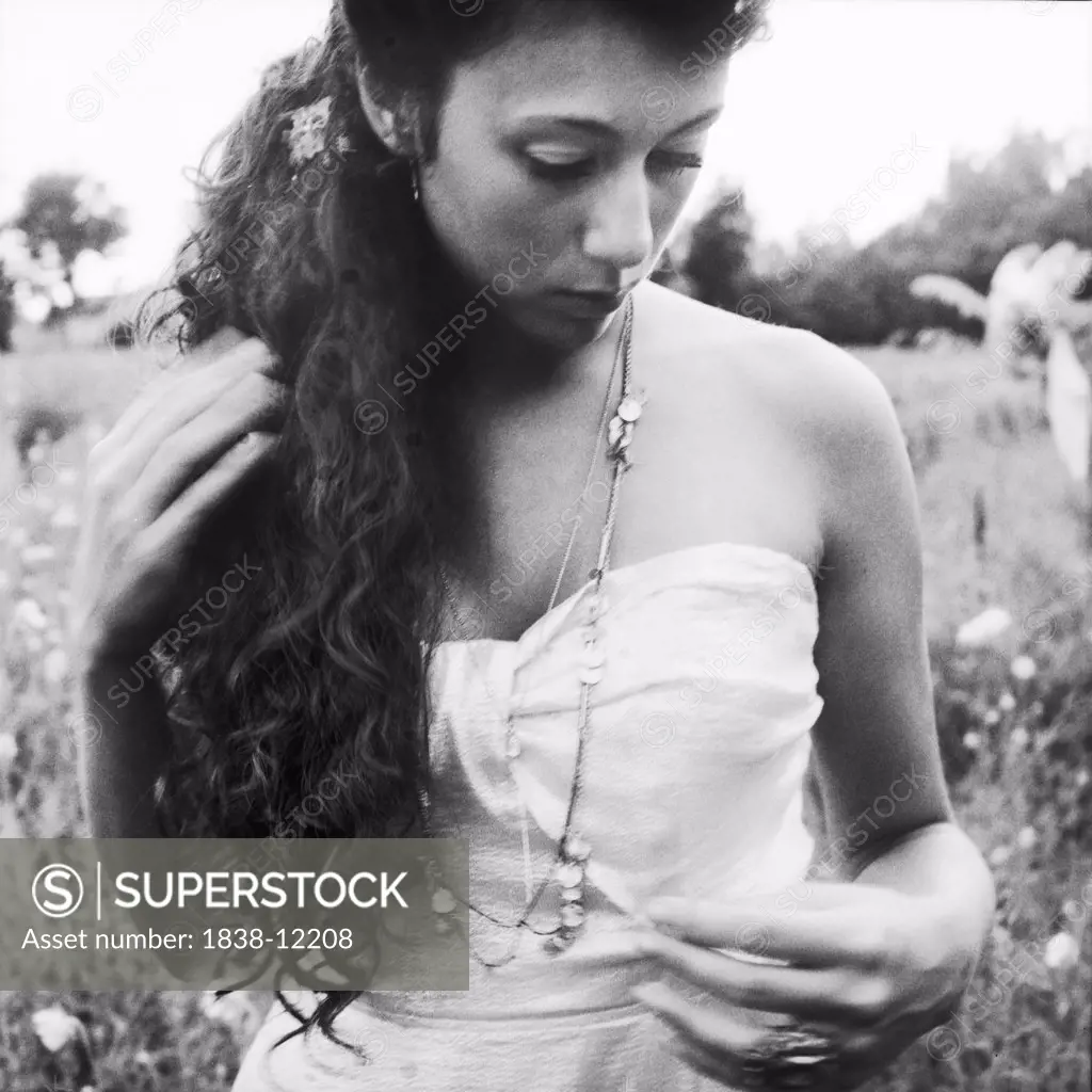 Solemn Woman With Long Curly Hair Wearing Strapless Dress in Field