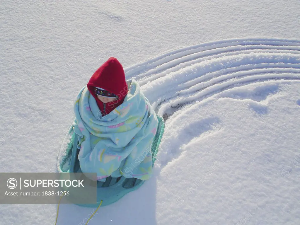 Child Wrapped in a Blanket on a Sled 