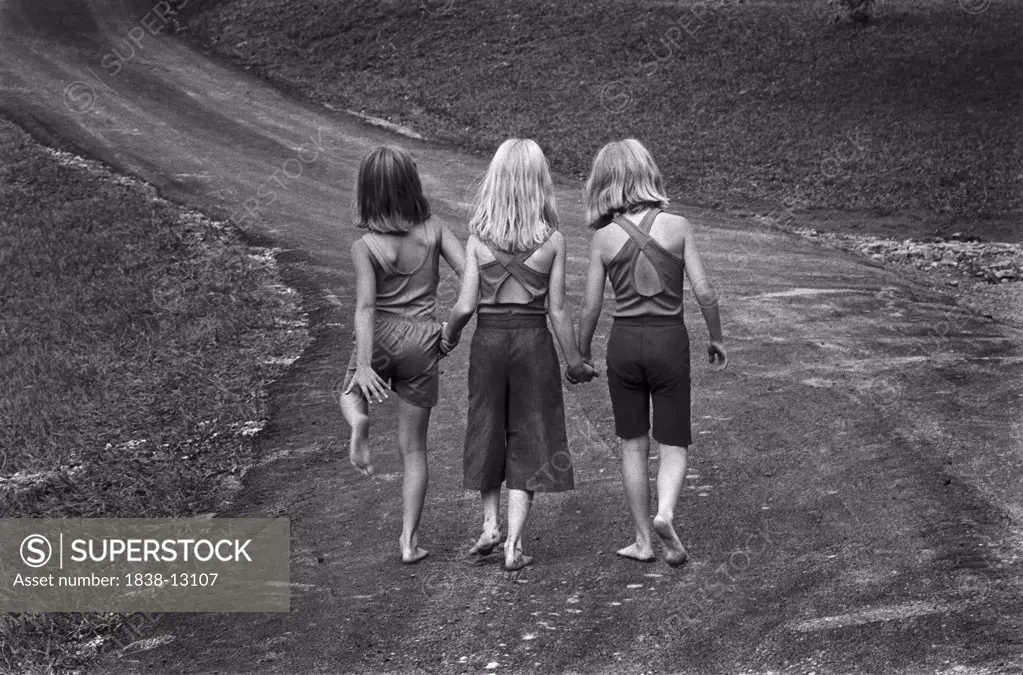 Three Barefoot Girls Holding Hands While Walking Down Path