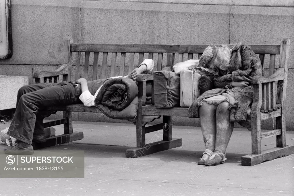 Homeless Man and Woman Sleeping on Park Bench