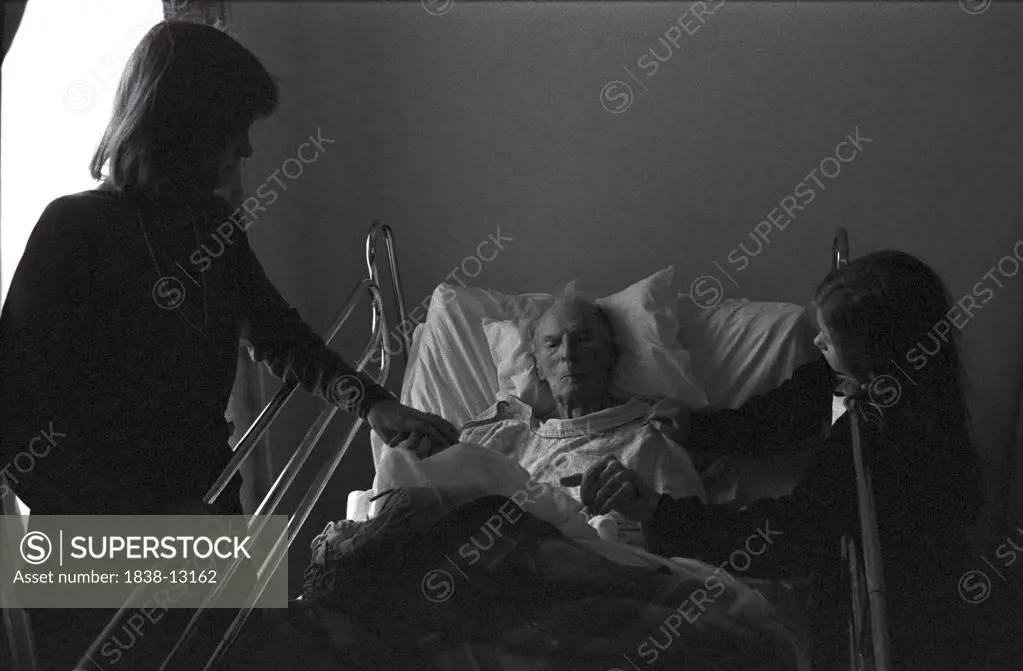 Woman and Girl Visiting Elderly Man in Hospital