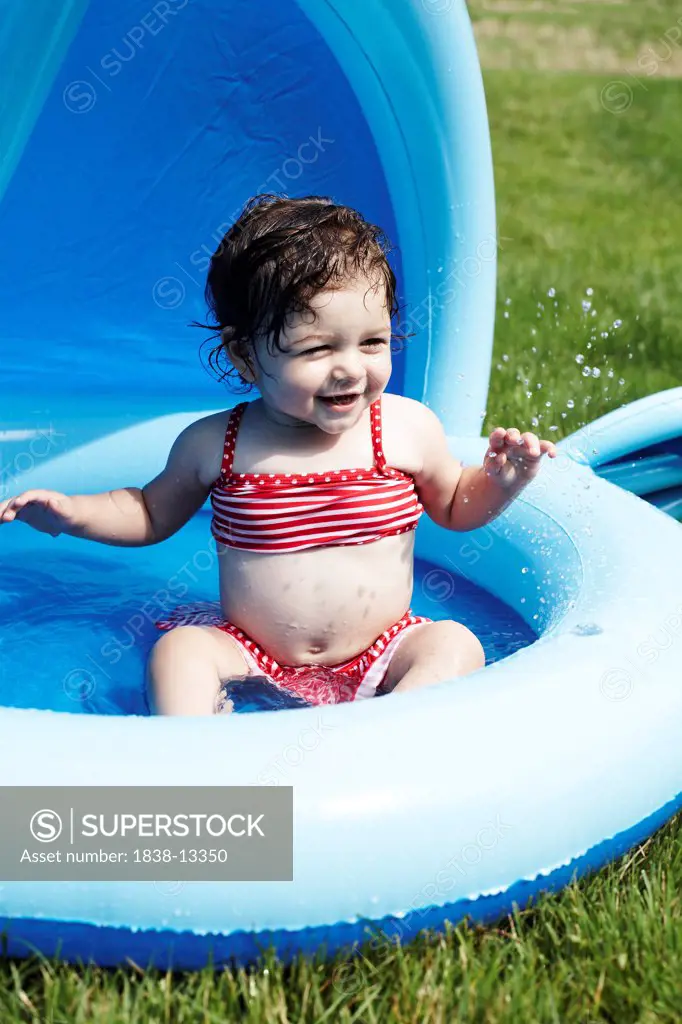 Young Girl in Red Bathing Suit Sitting in Small Pool