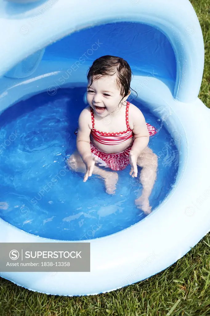 Young Girl in Red Bathing Suit Sitting in Small Pool, High Angle View