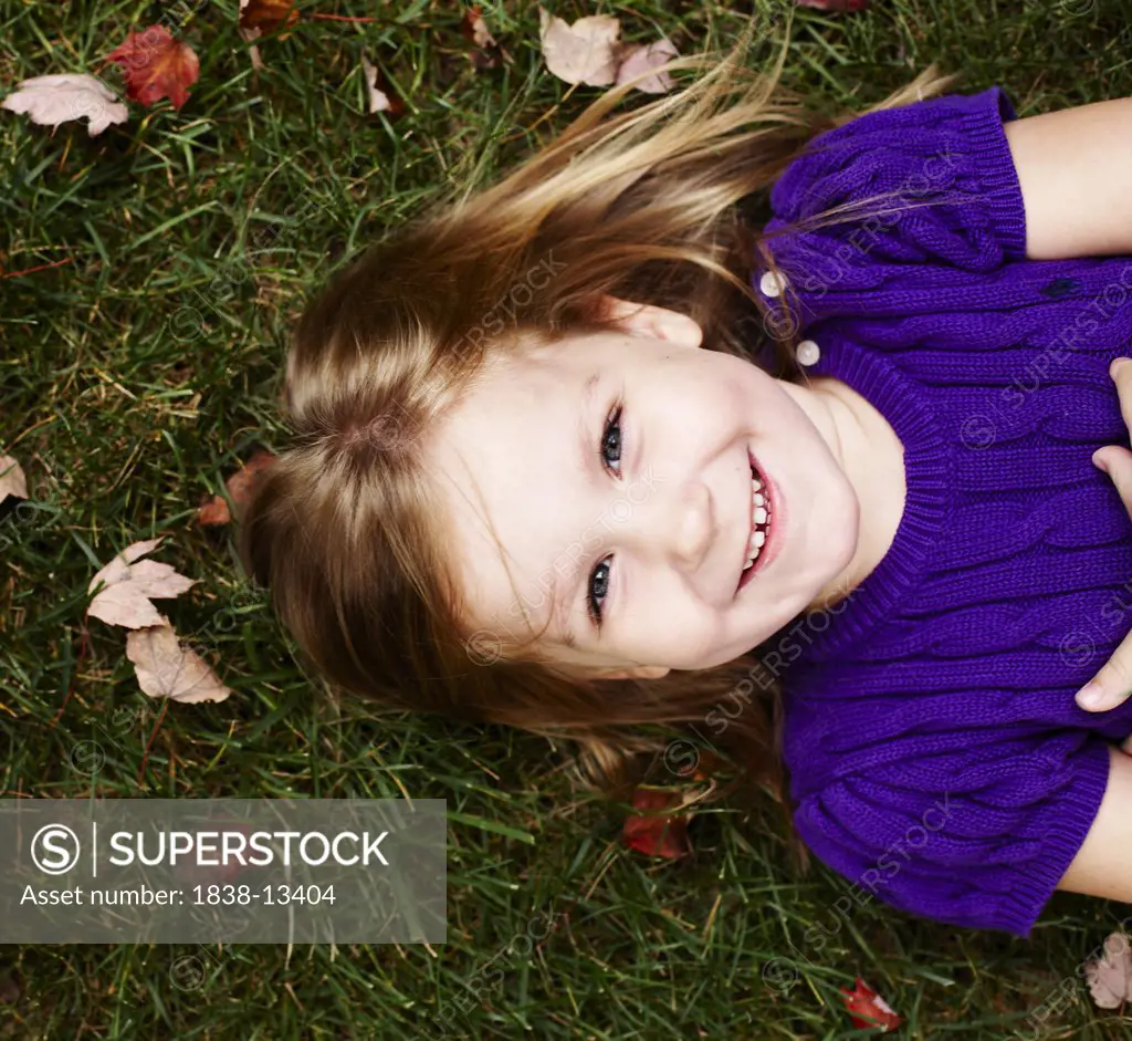 Smiling Young Girl Laying on Ground