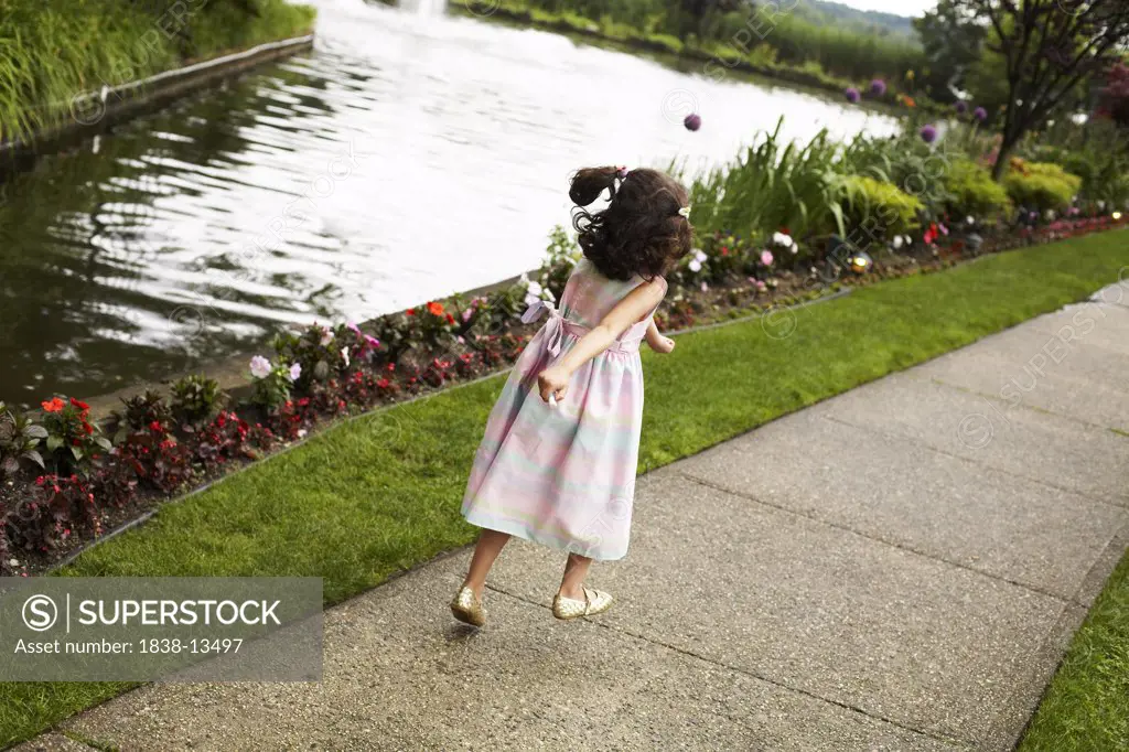 Young Girl Skipping on Sidewalk Along Lake