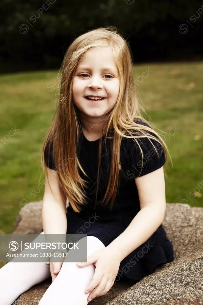 Young Smiling Girl Sitting on Rock
