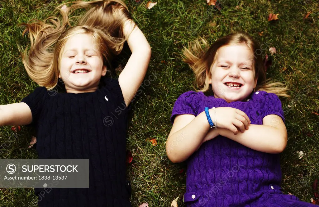 Two Young Girls Laying on Grass