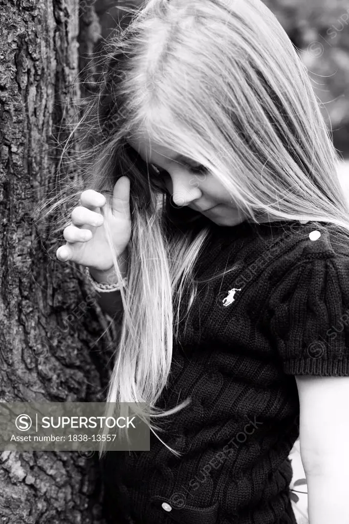 Young Girl Leaning Against Tree and Looking Down