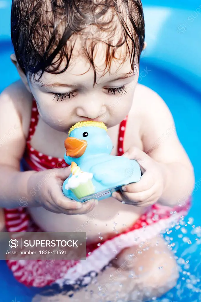 Young Girl Sitting in Pool With Rubber Duck