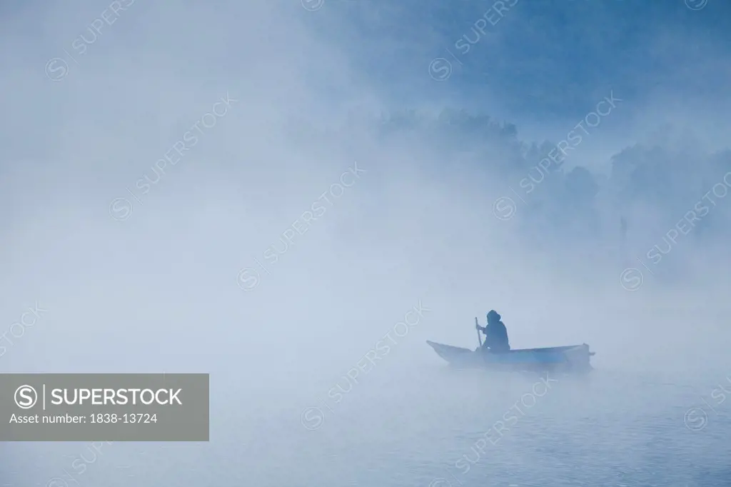 Man Rowing Boat on Misty Lake