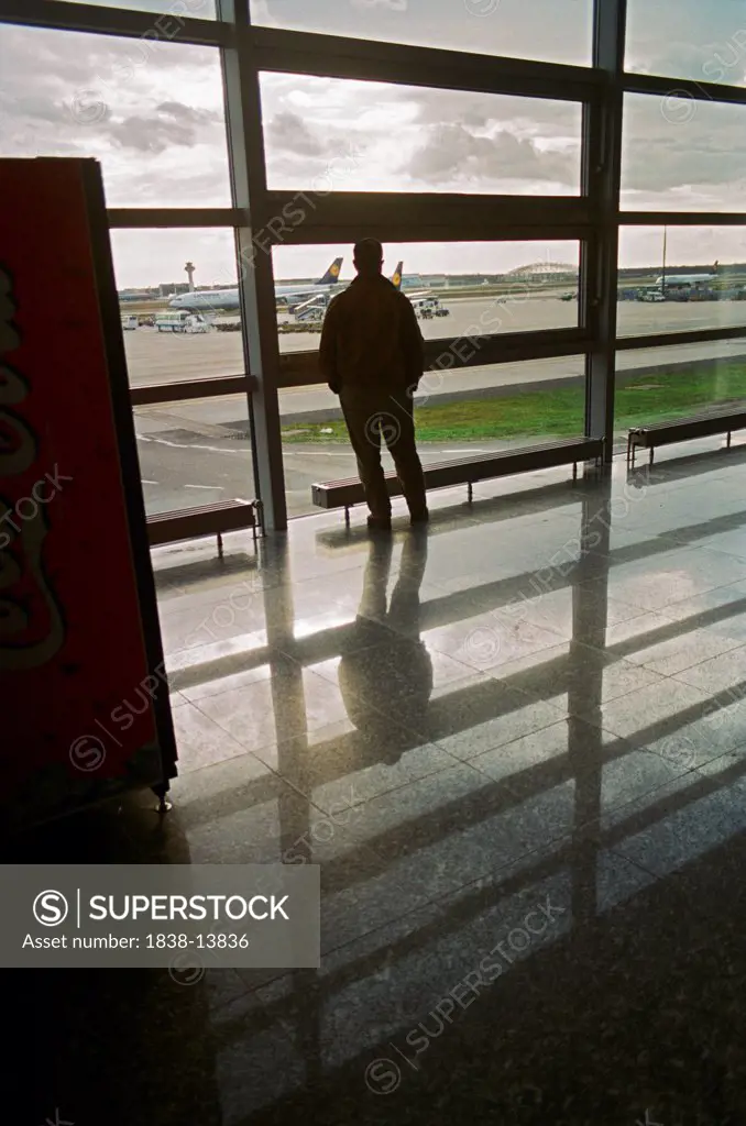 Man Looking at Airplanes Through Airport Window