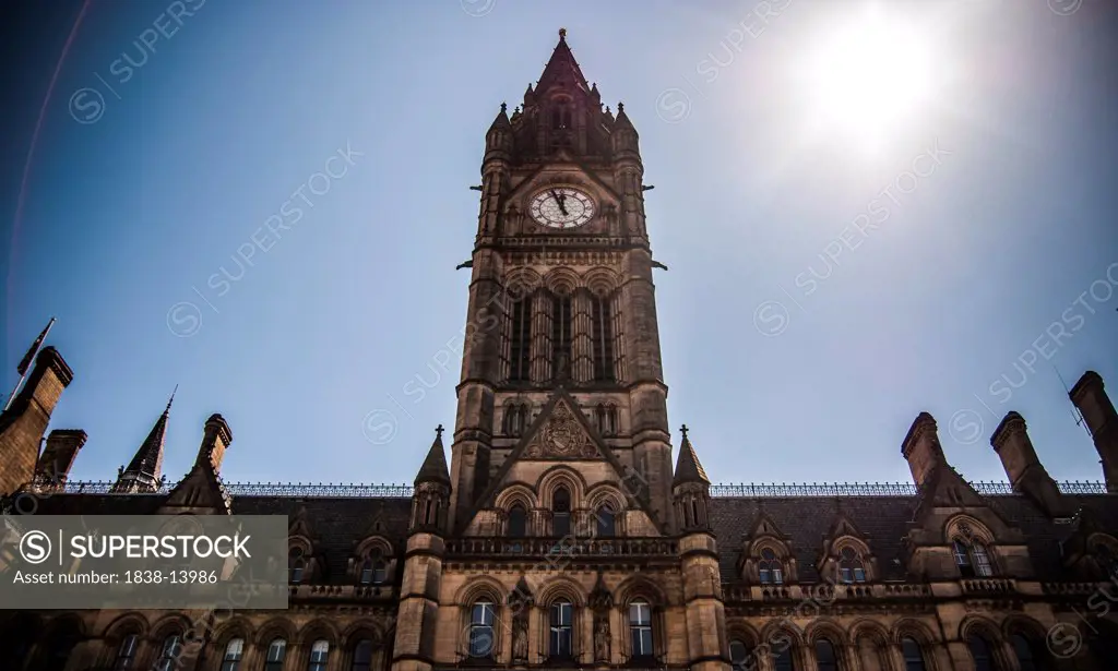 Dramatic Low Angle View of Manchester Town Hall Clock Tower with Sun in Sky, England, UK