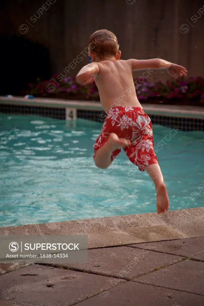 Young Boy Jumping into Swimming Pool