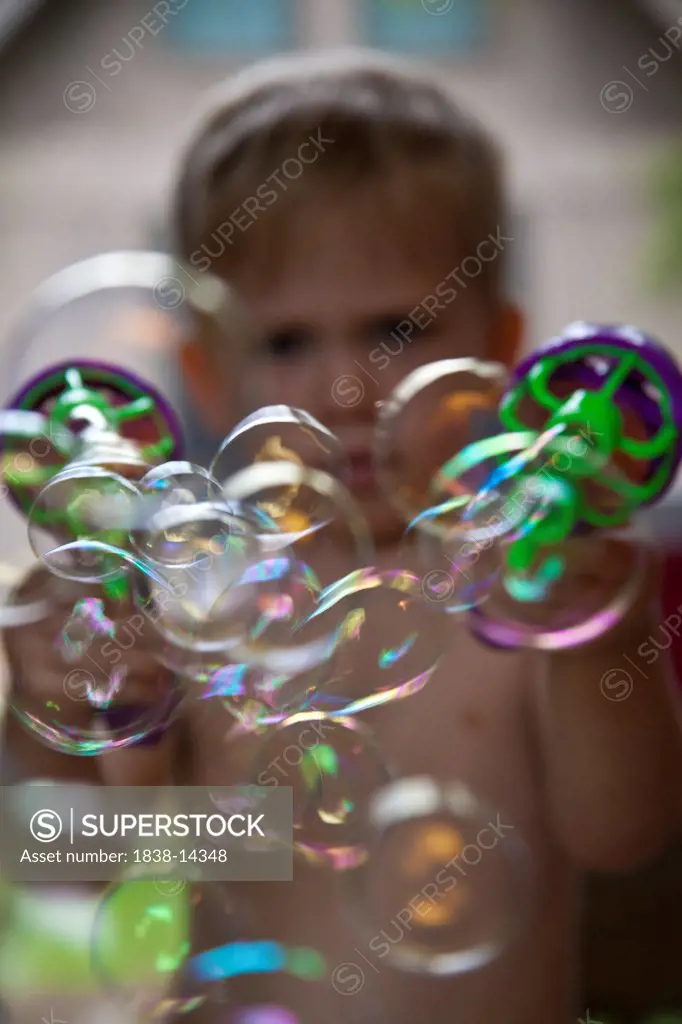Young Boy Shooting Bubbles From Toy Gun
