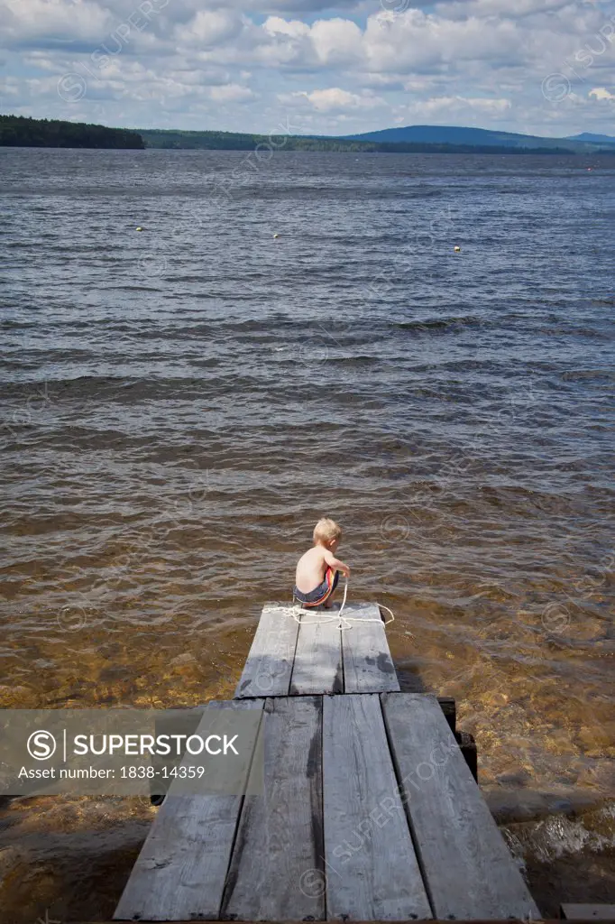 Young boy Playing With Rope at End of Dock on Lake