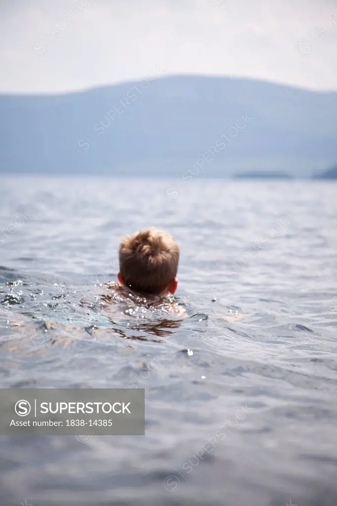 Young Boy Swimming in Lake, Rear View