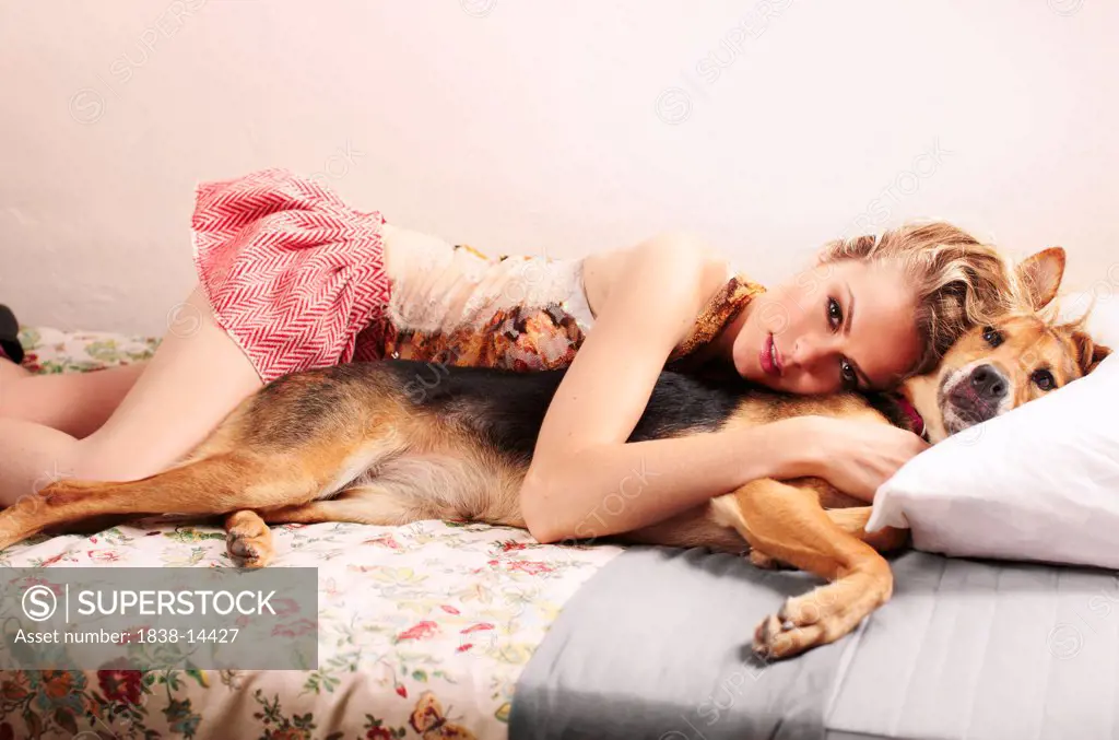 Young Woman and Dog Laying on Bed