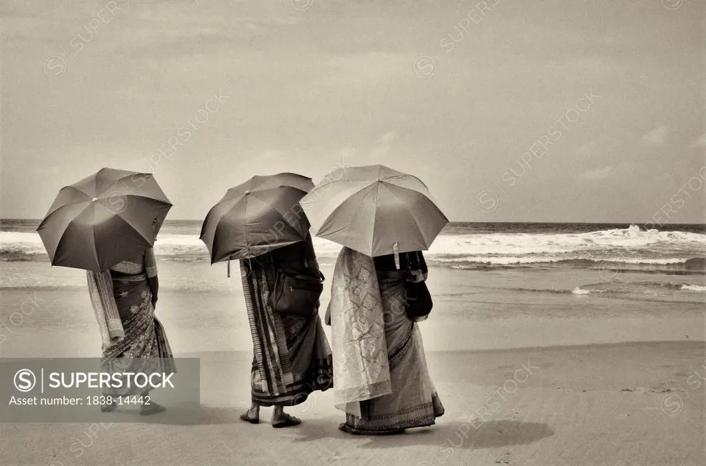 Three Women in Traditional Clothes on Beach With Umbrellas, Rear View, India