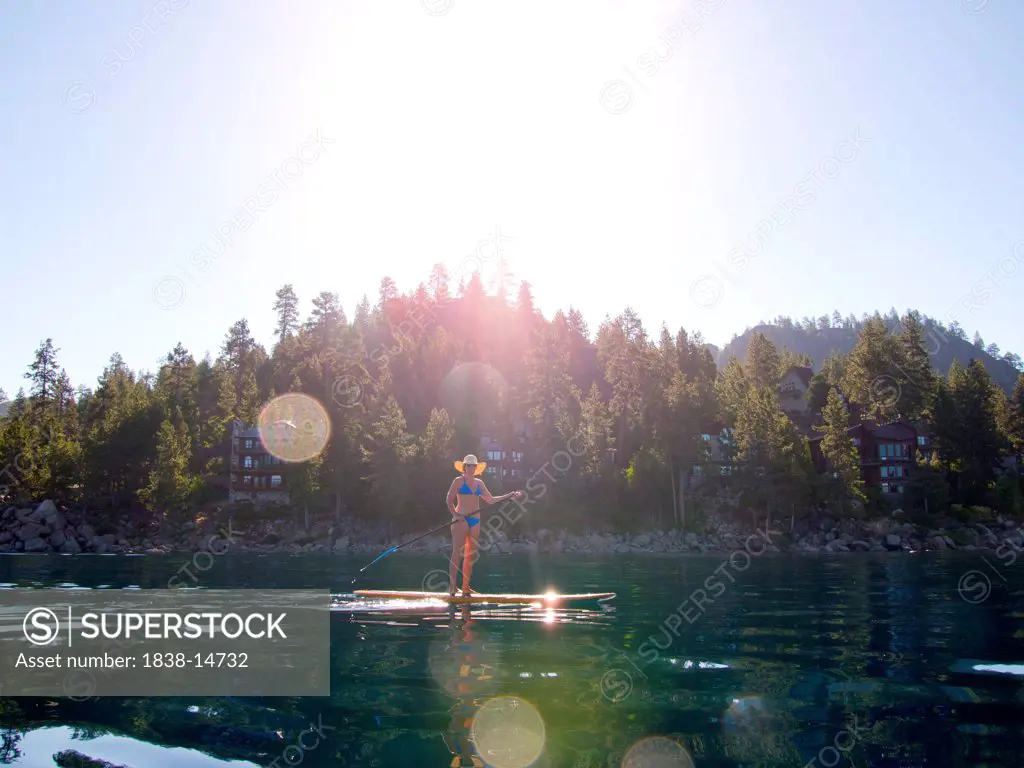 Woman Paddling on Lake with Sun Flares