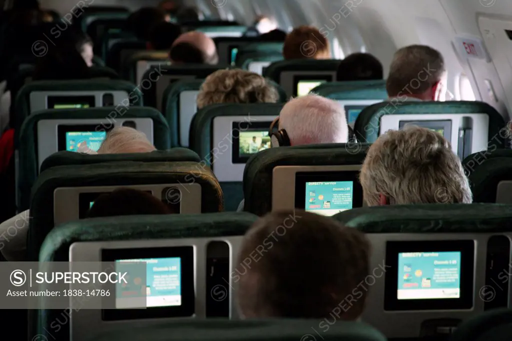 Passengers on Airplane Watching TV Screens, Rear View