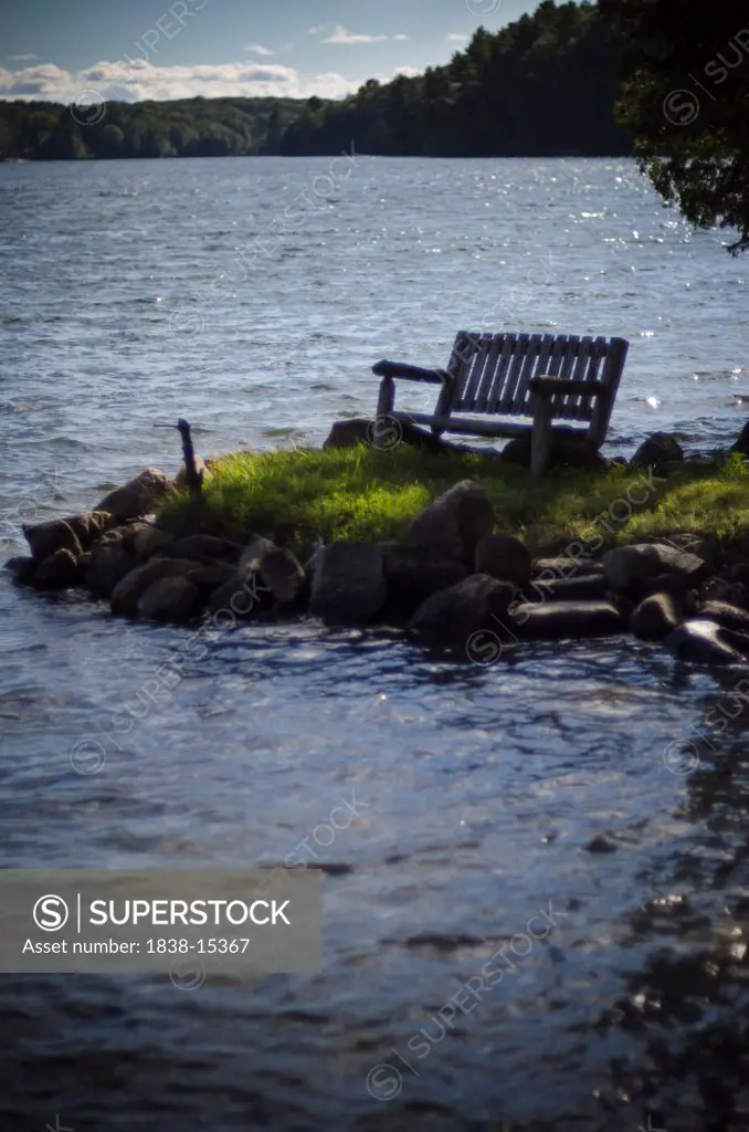 Wooden Bench on Grassy Rocky Area by Lake