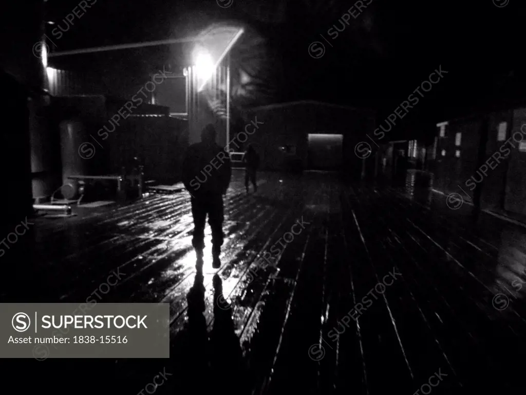 Two Men Walking on Fishing Dock at Night