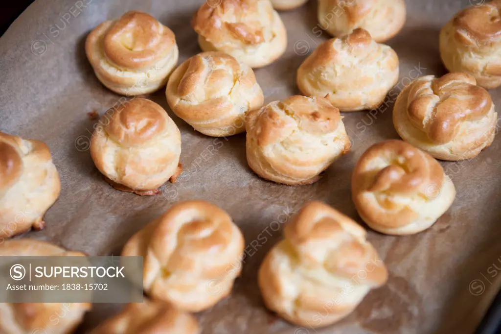 Freshly Baked Profiteroles on Parchment Paper, High Angle View