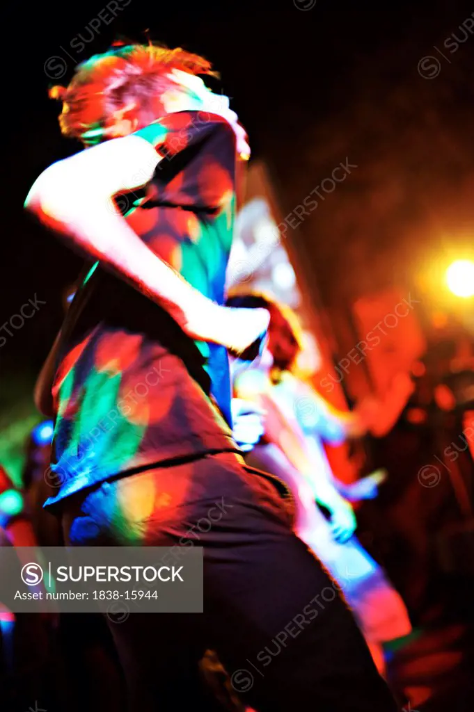 Young Man Dancing in Multi-Colored Lights at Dance Club